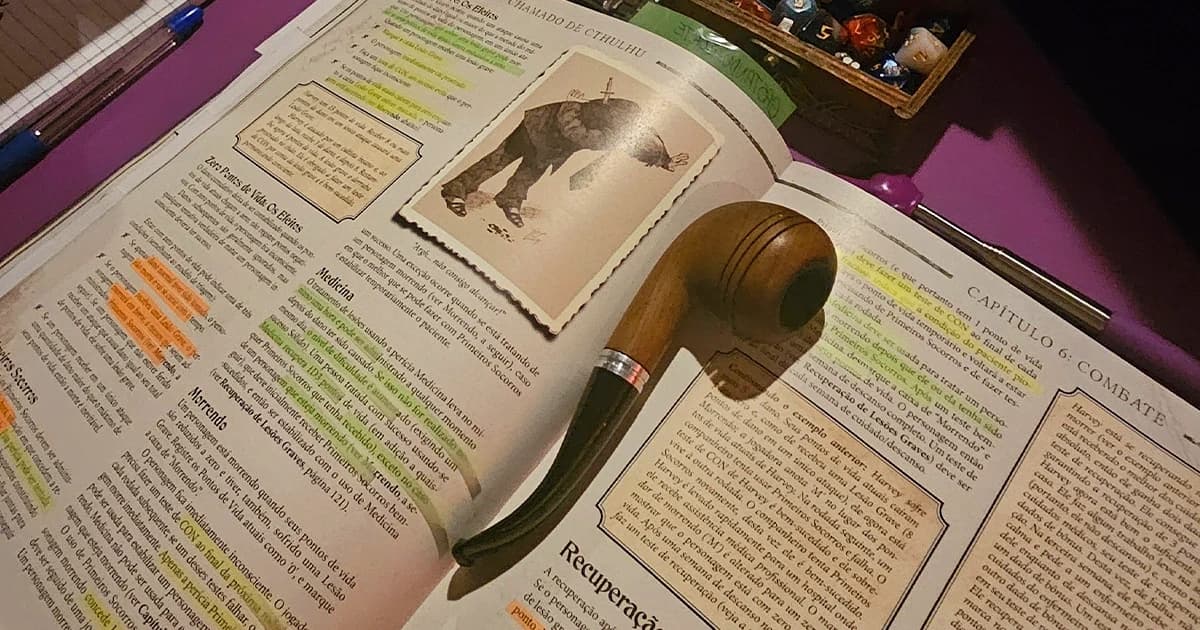 Livro de regras de Chamado de Cthulhu aberto no Capítulo 6, Combate, com trechos grifados e um cachimbo de madeira apoiado sobre as páginas.